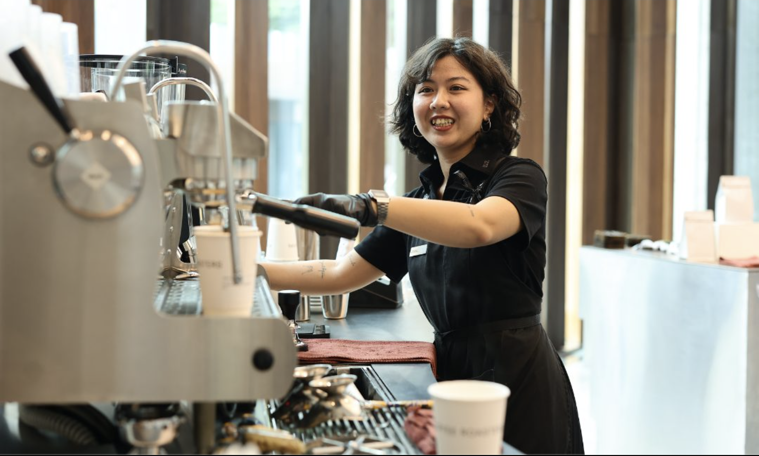 Smiling barista making coffee with an espresso machine in a modern cafe